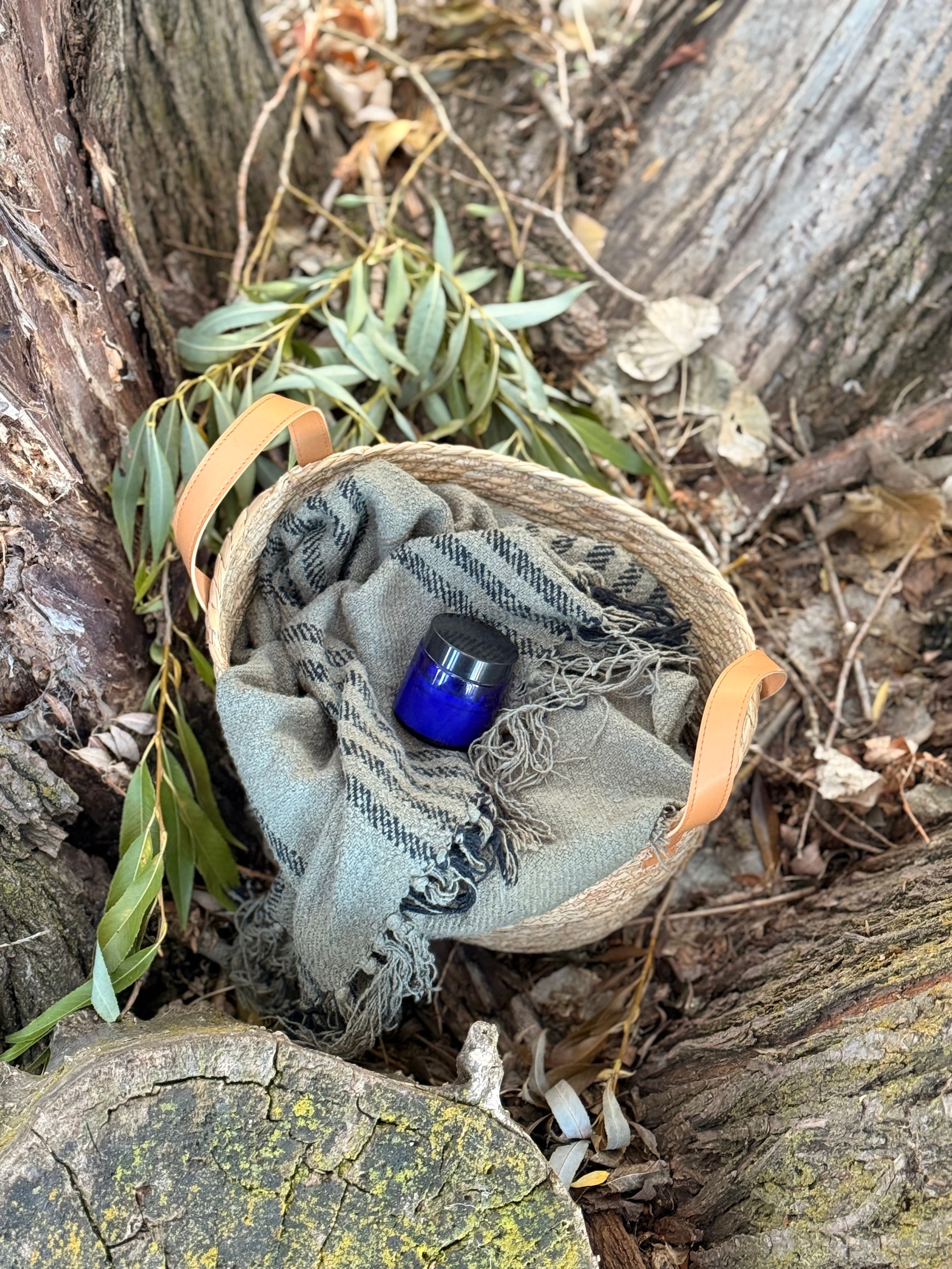 Green-tinted balm jar nestled in a woven basket